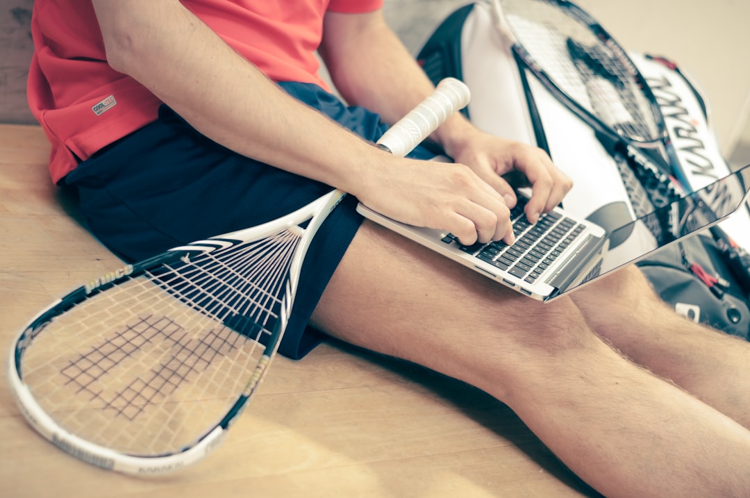 A high school athlete at a desk drafting a recruiting email on a laptop